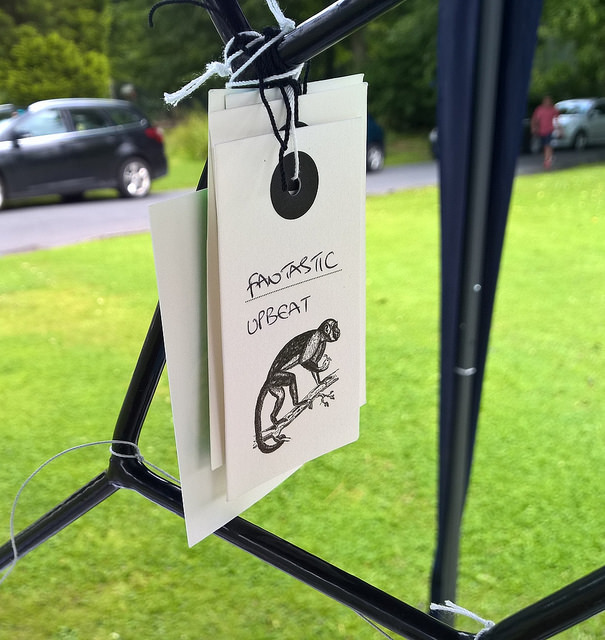Photo of a paper tag hanging from a small metal tree. The tag shows a Victorian illustration of a monkey. Under the monkey someone has written two words to describe the museum, which say fantastic and upbeat.