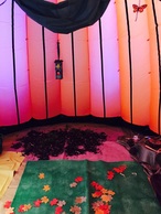 Inside of inflatable dome, lit up a cosy orange colour, with leaves and other natural objects on the floor ready for children to play with